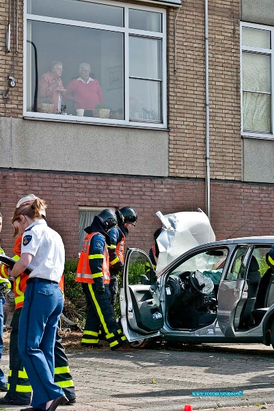 10042404.jpg - FOTOOPDRACHT:Zwijndrecht:24-04-2010:Foto: De geschrokken bewoners van de flat boven het ongeval kijken naar de brandweer die de auto op brand gevaar bekijkt. AUTOMOBILIST ZWAAR GEWOND NA BOTSING TEGEN FLAT ZWIJNDRECHT - Een 91-jarige automobilist uit Zwijndrecht is zaterdagochtend 24 april zwaar gewond geraakt toen hij met zijn auto tegen een flatgebouw reed. De man reed over een rotonde op de kruising van de Burgemeester Jansenlaan met de Officiersvliet toen hij van de rotonde afraakte, via het fietspad en enkele perkjes de weg overschoot en tegen een flat tot stilstand kwam. Brandweer- en ambulancepersoneel kwam ter plaatse en hebben de bestuurder uit zijn voertuig gehaald. Vervolgens is de man per ambulance naar het ziekenhuis gebracht. Zijn toestand is kritiek. Op de begane grond van de flat bevinden zich bergruimtes. Als gevolg van het ongeval ontstond een gat in de buitenmuur van de berging. De vereniging van eigenaars is hierover in kennisgesteld. Er is geen gevaar voor instorting. De bewoners van de flat boven de berging kwamen met de schrik vrij. De politie doet onderzoek naar de toedracht van het ongeval. Vermoedelijk is de man onwel geworden.  de oudere bewoners die boven het ongeval woonde waren erg geschrokken. Ze zaten net koffie in hun huis kamer te drinken toen de man onder hun tegen de flat aan reed.Deze digitale foto blijft eigendom van FOTOPERSBURO BUSINK. Wij hanteren de voorwaarden van het N.V.F. en N.V.J. Gebruik van deze foto impliceert dat u bekend bent  en akkoord gaat met deze voorwaarden bij publicatie.EB/ETIENNE BUSINK