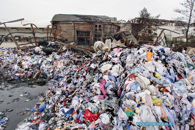 10061314.jpg - FOTOOPDRACHT:Dordrecht:13-06-2010:Dag na de Zeer grote brand bij Gebotex kilkade 23 Dordrecht, het bedrijf importeur/grossiers van bruikbare kleding recyclingZEER GROTE BRAND BIJ KLEDINGRECYCLEBEDRIJFDORDRECHT - In de nacht van zaterdag op zondag 13 juni heeft een zeer grote brand gewoed bij een kledingrecylcebedrijf. Rond 1.15 uur kwam de melding dat er band was uitgebroken in het bedrijf aan de Kilkade. Hierop rukten diverse brandweervoertuigen uit. Kort na het ontstaan van de brand schaalde de brandweer op naar zeer grote brand en werd vanwege de omvang van de brand besloten over te gaan tot GRIP 1 (Gecoördineerde Regionale Incidentenbestrijding Procedure). Diverse brandweerkorpsen uit de regio kwamen met groot materieel ter plaatse om de brand te bestrijden en te voorkomen dat de brand oversloeg naar de rest van het bedrijf. Uit voorzorg kwam ook een blusboot ter plaatse om eventueel vanaf het water aan de achterzijde van het pand bluswerkzaamheden te verrichten. Dit bleek uiteindelijk niet nodig. De brandweer is de hele nacht met man en macht bezig geweest het vuur te  bestrijden. Om 6.00 uur kon het sein brandmeester worden gegeven.Als gevolg van de brand werden twee hallen van het bedrijf in as gelegd. De brandweer wist te voorkomen dat de brand oversloeg naar een derde hal achter de twee uitgebrandde hallen. Wel ontstond er schade aan de gevel van de derde hal door de hitte van de brand. Twee naastgelegen panden van hetzelfde bedrijf bleven gespaard. Bij de brand vielen geen slachtoffers. Als gevolg van de brand was er sprake van een forse rookontwikkeling. De rook trok weg in de richting van de wijk Sterrenburg en zorgde ervoor dat op sommige plekken roetdeeltjes neersloegen. De brandweer verrichtte diverse metingen. Hieruit bleek dat er geen gevaarlijke stoffen zijn vrij gekomen en dat de brand geen gevaar opleverde voor de omgeving.De oorzaak van de brand is niet bekend. De Politie Zuid-Holland-Zuid stelt hiernaar een onderzoek in. De brandweer verw