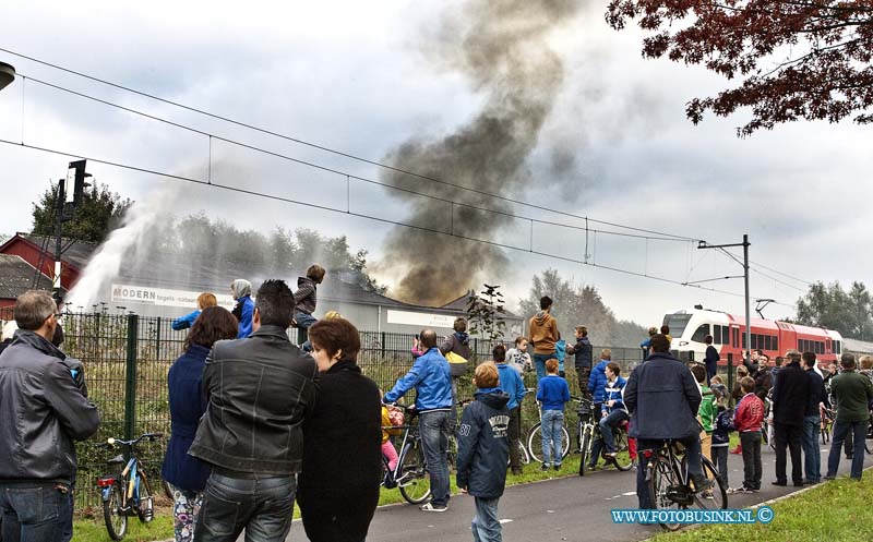 13101201.jpg - FOTOOPDRACHT:Hardinxveld-Giessendam:12-10-2013:Zeer grote brand in een loods in Hardinxveld-Giessendam. In de voormalige tegelhandel Modern aan de Giessenzoom.Het complex te koop. De brand is volgens de brandweer begonnen in een loods van 100 bij 50 meter. De brandweer gaf omwonenden het advies om uit de rook te blijven en ramen en deuren gesloten te houden. Er is asbest bij de brand vrijkomen. De Parallelweg is ter plaatse ontruimd. Het treinverkeer is stilgelegd tussen Gorinchem en Hardinxveld-Giessendam. Reizigers moeten rekening houden met een uur extra reistijd. De NS verwacht dat de stremming rond 18.30 uur is opgelost.Deze digitale foto blijft eigendom van FOTOPERSBURO BUSINK. Wij hanteren de voorwaarden van het N.V.F. en N.V.J. Gebruik van deze foto impliceert dat u bekend bent  en akkoord gaat met deze voorwaarden bij publicatie.EB/ETIENNE BUSINK