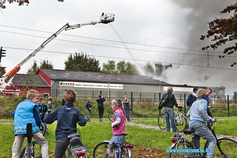 13101203.jpg - FOTOOPDRACHT:Hardinxveld-Giessendam:12-10-2013:Zeer grote brand in een loods in Hardinxveld-Giessendam. In de voormalige tegelhandel Modern aan de Giessenzoom.Het complex te koop. De brand is volgens de brandweer begonnen in een loods van 100 bij 50 meter. De brandweer gaf omwonenden het advies om uit de rook te blijven en ramen en deuren gesloten te houden. Er is asbest bij de brand vrijkomen. De Parallelweg is ter plaatse ontruimd. Het treinverkeer is stilgelegd tussen Gorinchem en Hardinxveld-Giessendam. Reizigers moeten rekening houden met een uur extra reistijd. De NS verwacht dat de stremming rond 18.30 uur is opgelost.Deze digitale foto blijft eigendom van FOTOPERSBURO BUSINK. Wij hanteren de voorwaarden van het N.V.F. en N.V.J. Gebruik van deze foto impliceert dat u bekend bent  en akkoord gaat met deze voorwaarden bij publicatie.EB/ETIENNE BUSINK